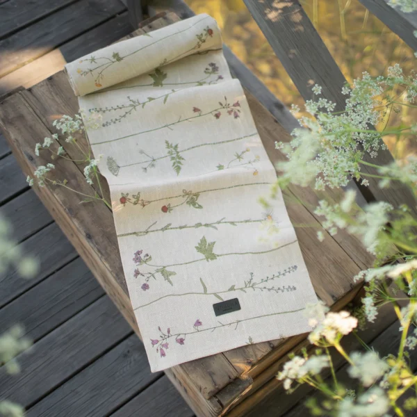 Beige bordslöpare i 100 % linne med blommor som mönster, tillverkad av NORDRÅ Sweden som säljer presenter och inredning.