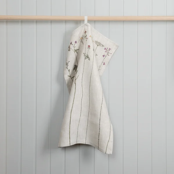 Beige kökshandduk i 100 % linne med blommor som mönster, tillverkad av NORDRÅ Sweden som säljer presenter och inredning.