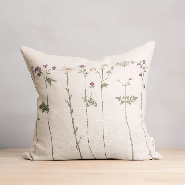 Beige kudde i 100 % linne med blommor som mönster, tillverkad av NORDRÅ Sweden som säljer presenter och inredning.