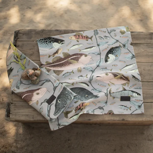 Gråa servetter i linneblandning med fiskar som mönster, tillverkad av NORDRÅ Sweden som säljer presenter och inredning.