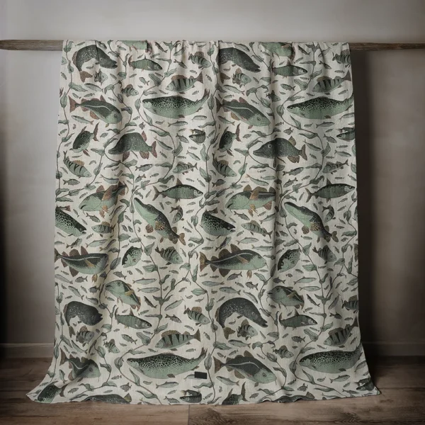 Grön och beige bordsduk i linne med fiskar som mönster, tillverkad av NORDRÅ Sweden som säljer presenter och inredning.