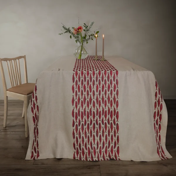 Röd och beige bordsduk i linne med fiskar som mönster, tillverkad av NORDRÅ Sweden som säljer presenter och inredning.