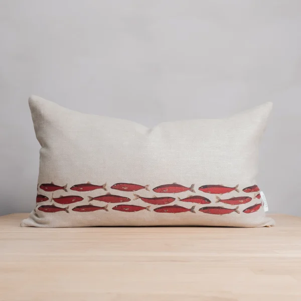 Röd och beige kudde i linne med fiskar som mönster, tillverkad av NORDRÅ Sweden som säljer presenter och inredning.