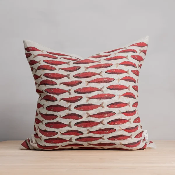 Röd och beige kudde i linne med fiskar som mönster, tillverkad av NORDRÅ Sweden som säljer presenter och inredning.