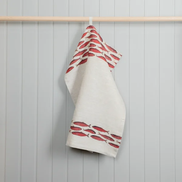 Röd och beige kökshandduk i linne med fiskar som mönster, tillverkad av NORDRÅ Sweden som säljer presenter och inredning.