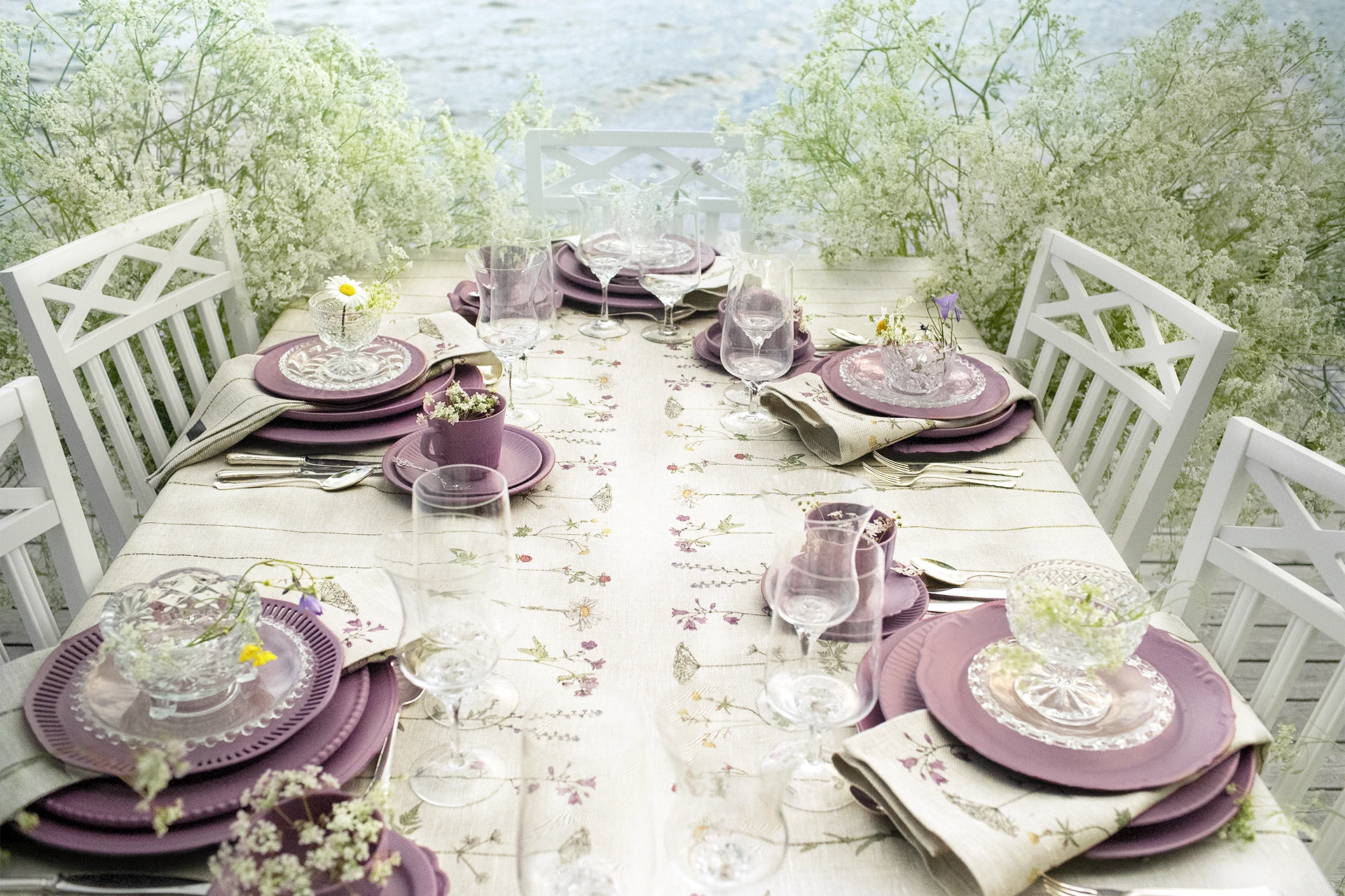 Midsommardukning med blommig linneduk från NORDRÅ Sweden med havet i bakgrunden och rosa servis