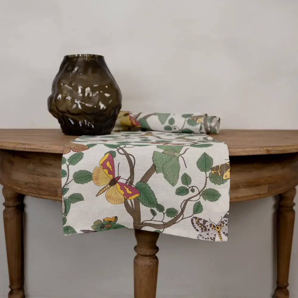 Beige och grön bordlöpare i 100 % linne med fjärilsmönster, tillverkad av NORDRÅ Sweden som säljer presenter och inredning.